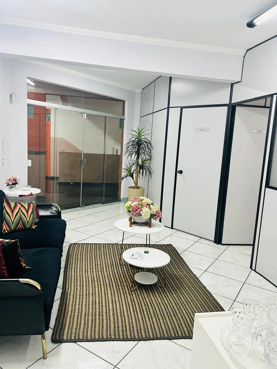 Sofá escuro, tapete e mesa de centro na sala do consultório de Jandira