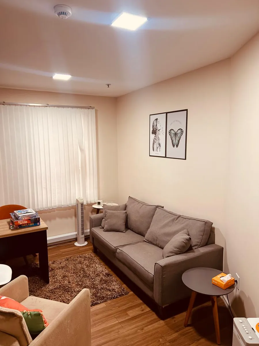 Sala de psicoterapia com sofá, tapete e quadros no consultório de Barueri