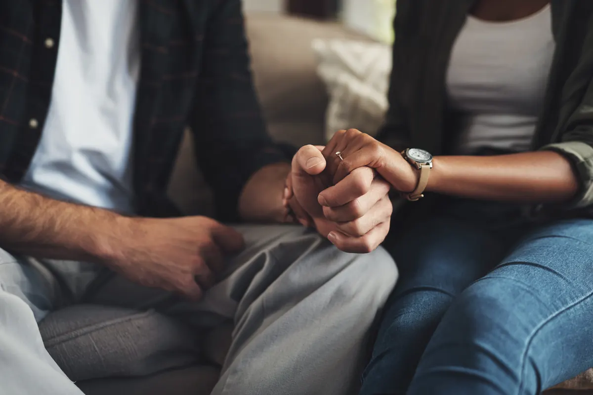 Casal sentado de mãos dadas em um sofá